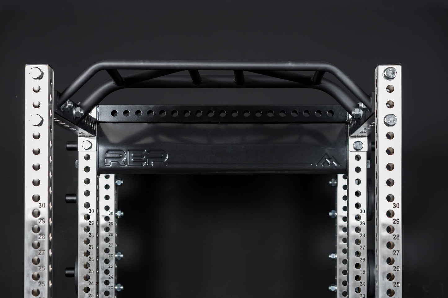 Close up of the stamped Logo Plate Crossmember 2.0 on a REP power rack in front of a black background
